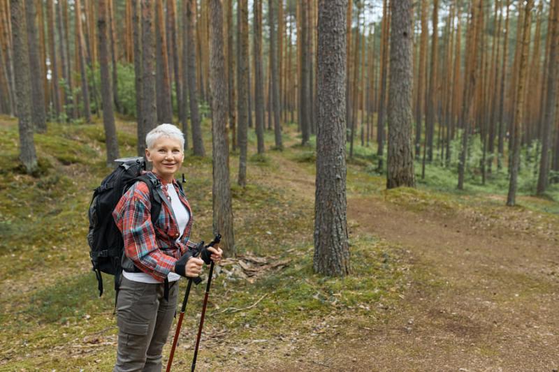 Starsza kobieta spacerująca po lesie
